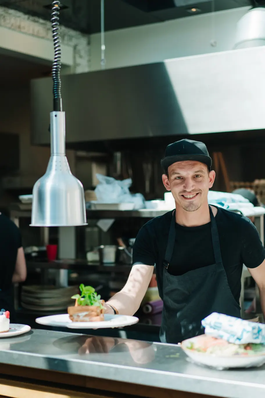 Chef in horecazaak die lachend camera in kijkt