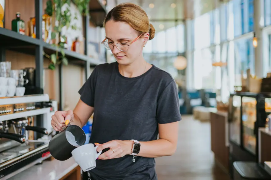 Barista schenkt melk in koffie